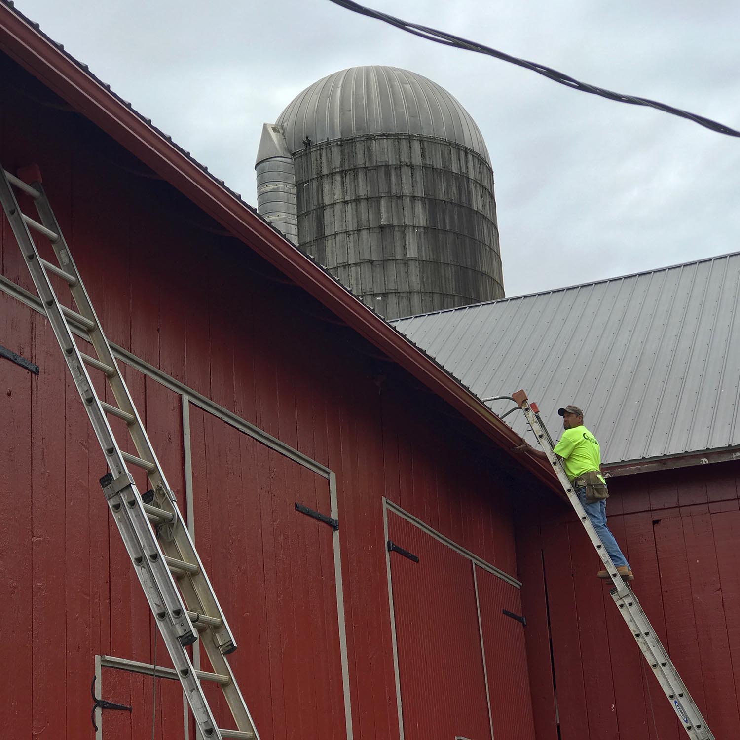 New gutters being installed on a barn roof.